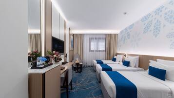 A hotel room with two beds, a desk, a chair, a TV, and a window with curtains.
