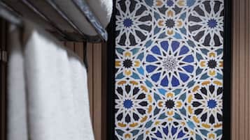 A framed geometric pattern on a wall, a towel rack with a white towel, and wooden paneling.