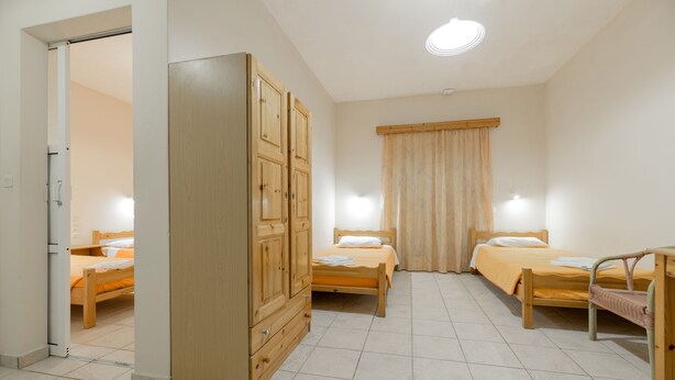 A bedroom with two wooden beds, a wardrobe, and a small table. - Pink Panther Studios & Apartments (Zakynthos)
