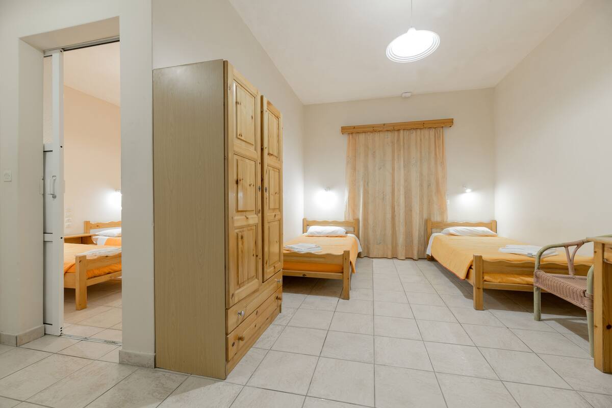 A bedroom with two wooden beds, a wardrobe, and a small table.