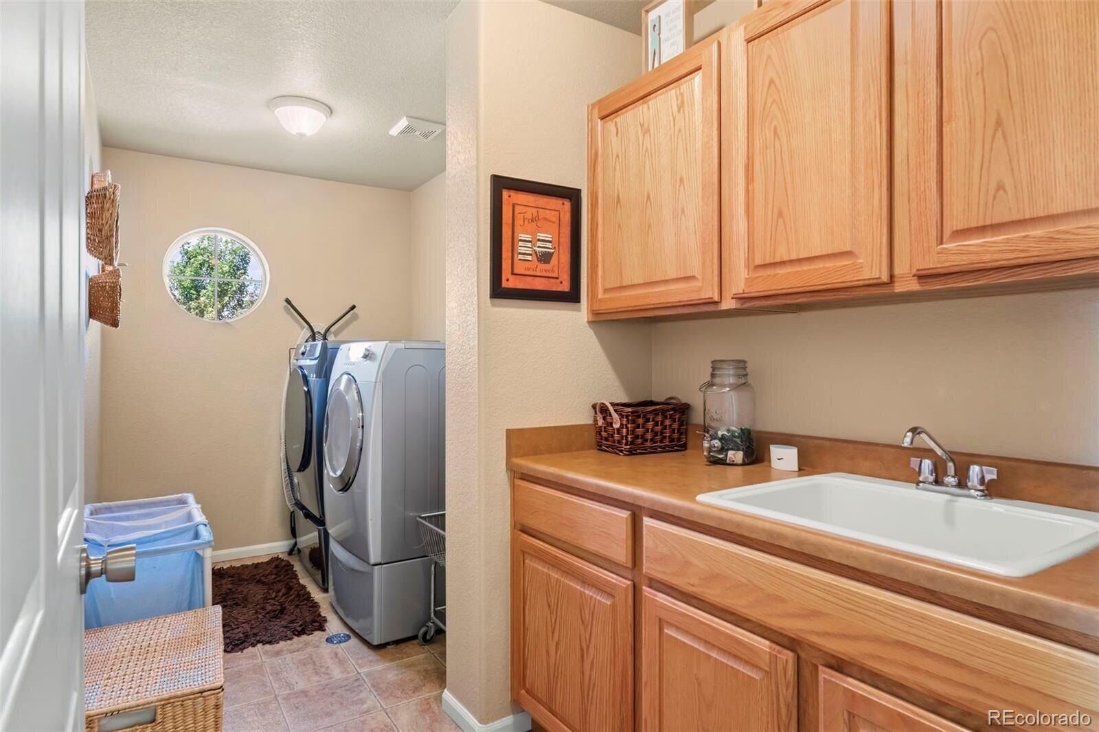 A compact kitchen with wooden cabinets, a sink, and a laundry area with a washing machine.