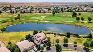 Een woongebied met huizen, een golfbaan en een meer.