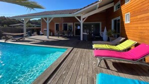 A wooden house with a pool, outdoor furniture, and a covered patio area.