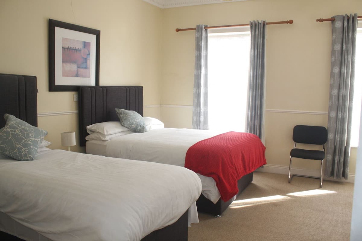Habitación de hotel con dos camas, una silla y un cuadro en la pared.