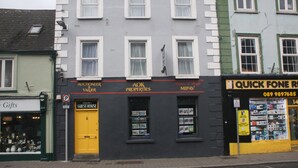 A building with a black storefront, a yellow door labeled "Guest House," and a sign for "Quick Fone Repair." - No 13 Townhouse (Kilkenny)