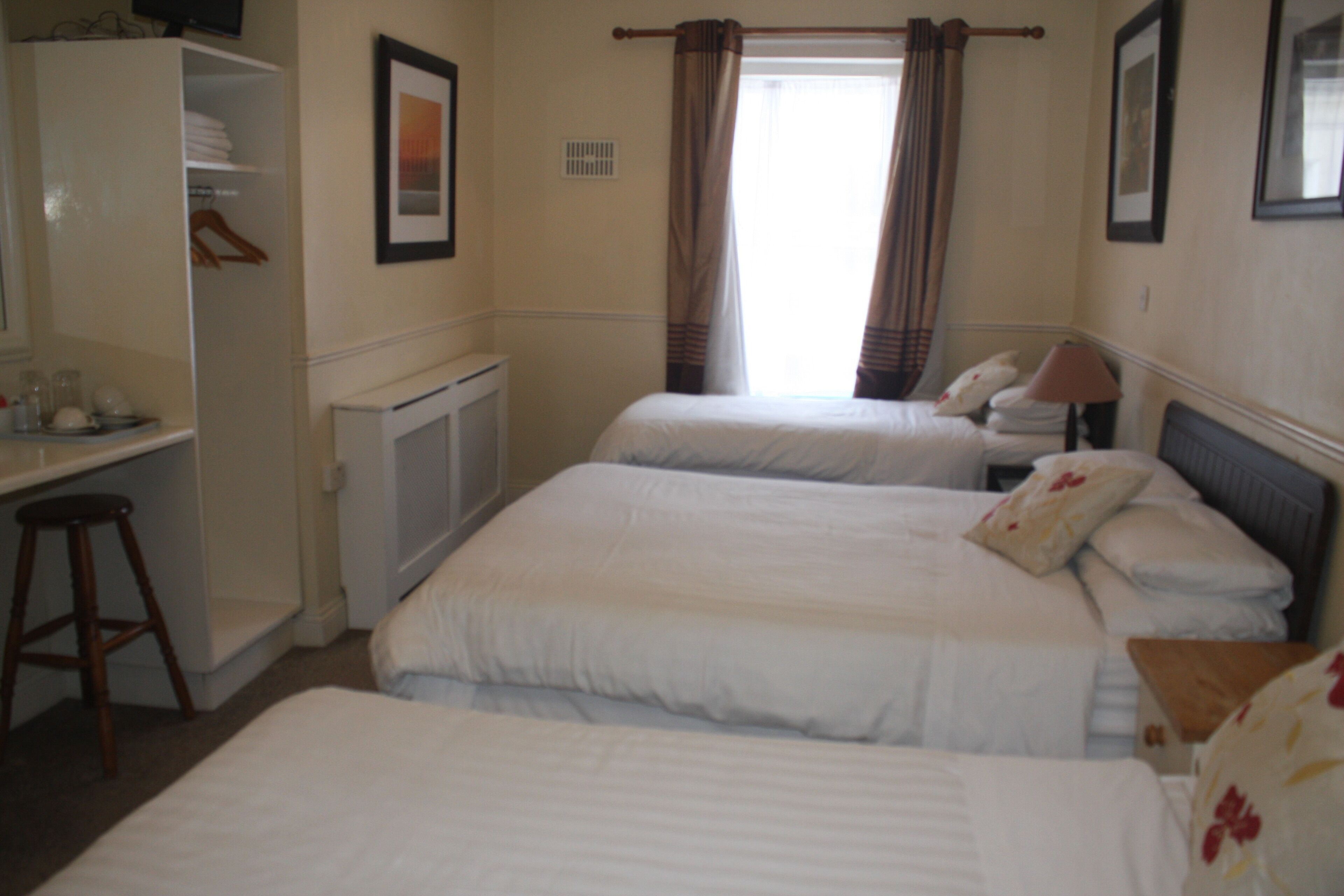 A hotel room with two beds, a desk, and a wardrobe.