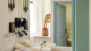 A bathroom with a white sink, a mirror, a hairdryer, and a wicker lamp. - Finca Maltés San José (Nijar)