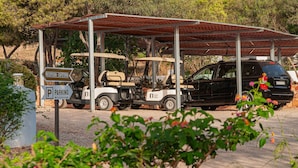 A covered parking area with a golf cart and a black SUV. - Finca Maltés San José (Nijar)