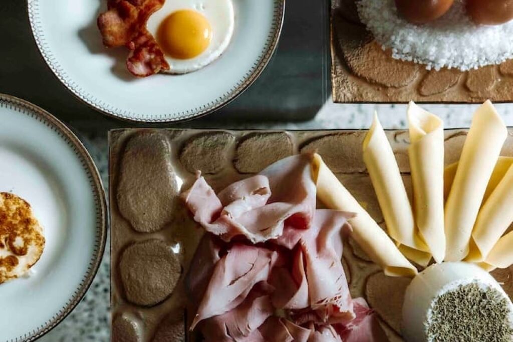 Ein Frühstückstisch mit Eiern, Speck, Schinken und Käse.