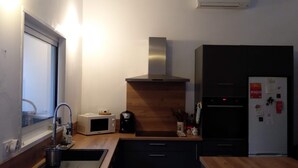 Une cuisine moderne dotée d’un plan de travail en bois, d’appareils électroménagers intégrés et d’une hotte en acier inoxydable.