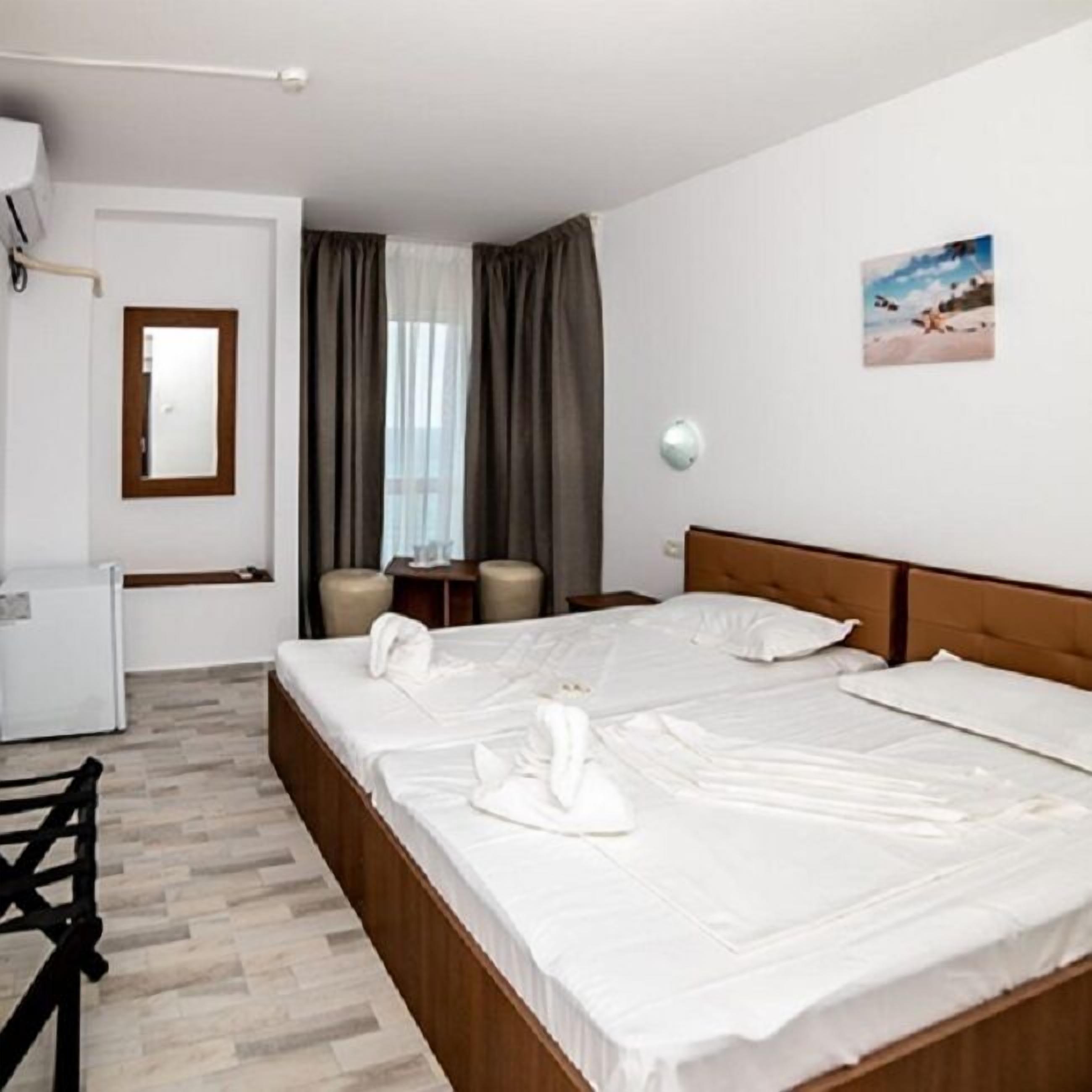A hotel room with two beds, a desk, a chair, and a small table.