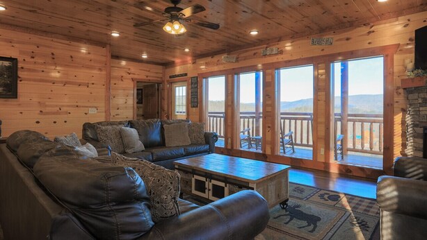 A log cabin interior with a large sofa, a coffee table, and a fireplace.