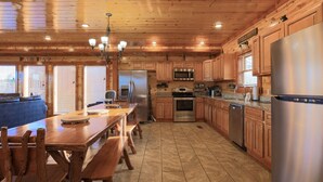 A spacious kitchen with wooden cabinets, a stainless steel refrigerator, and a dining area with a wooden table and benches.