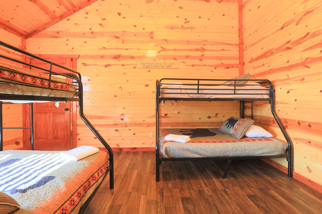 A cabin with two bunk beds, wooden walls, and a wooden floor.
