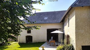 Een huis met een stenen terras, een tafel met stoelen en een witte parasol.