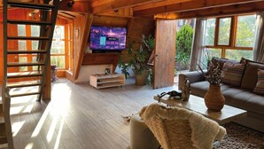 A cozy cabin interior with a wooden interior, a television mounted on the wall, a sofa, a coffee table, and a plant. - Renovated and Harmonious Cabin in Valle de Bravo (Valle de Bravo)