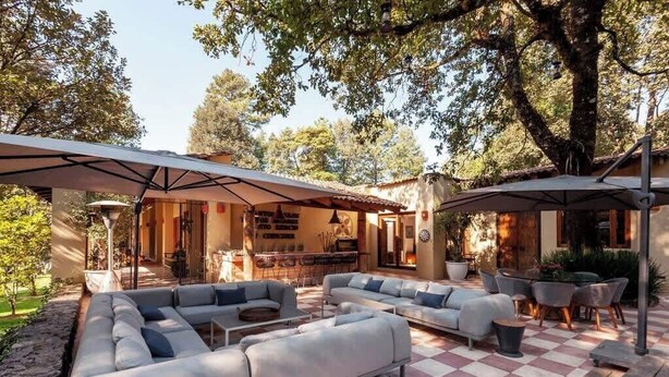 An outdoor seating area with a checkered floor, grey sofas, and umbrellas. - Spectacular House with Jacuzzi and Huge Garden (San Simón el Alto)