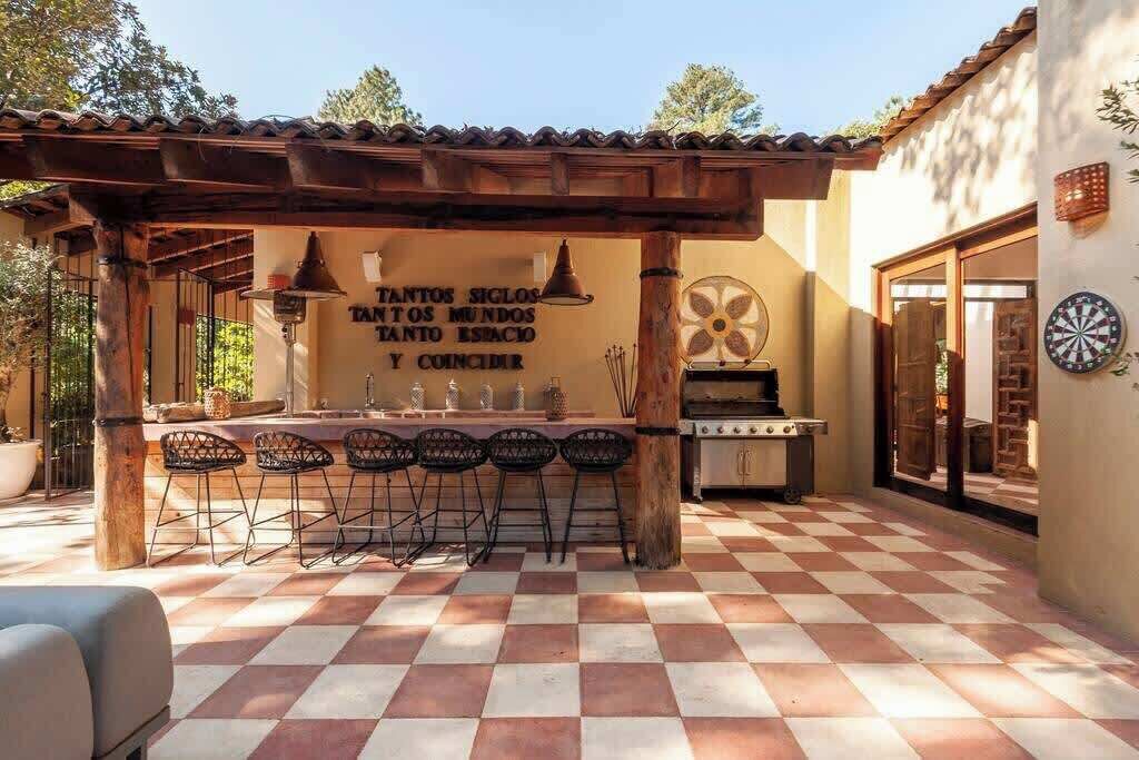 A patio with a checkered floor, a barbecue grill, and a table with chairs.