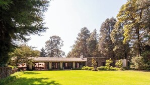 A house with a covered patio, surrounded by a well-maintained lawn and trees. - Spectacular House with Jacuzzi and Huge Garden (San Simón el Alto)