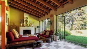 A cozy living room with a checkered floor, a fireplace, and a large window overlooking a garden. - Spectacular House with Jacuzzi and Huge Garden (San Simón el Alto)