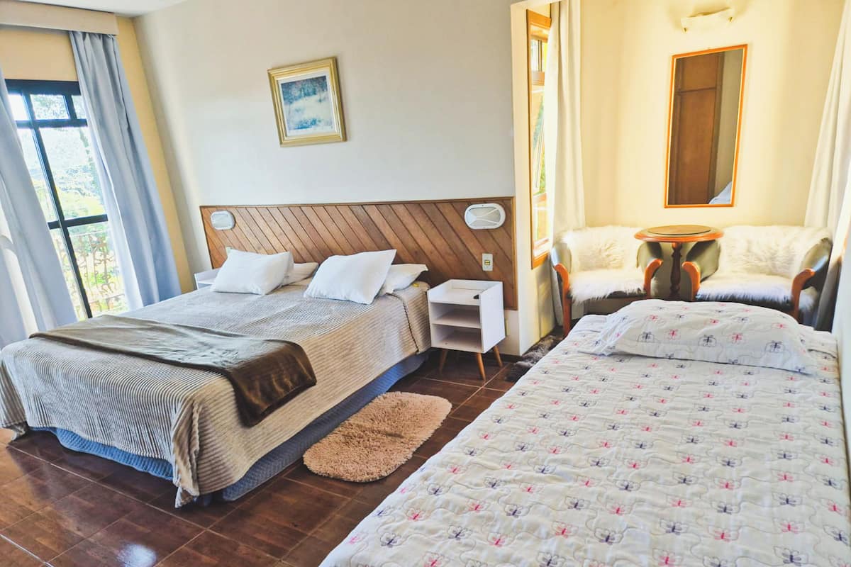 Une chambre d’hôtel avec deux lits, une tête de lit en bois, une petite table de chevet, une chaise et une fenêtre avec des rideaux.