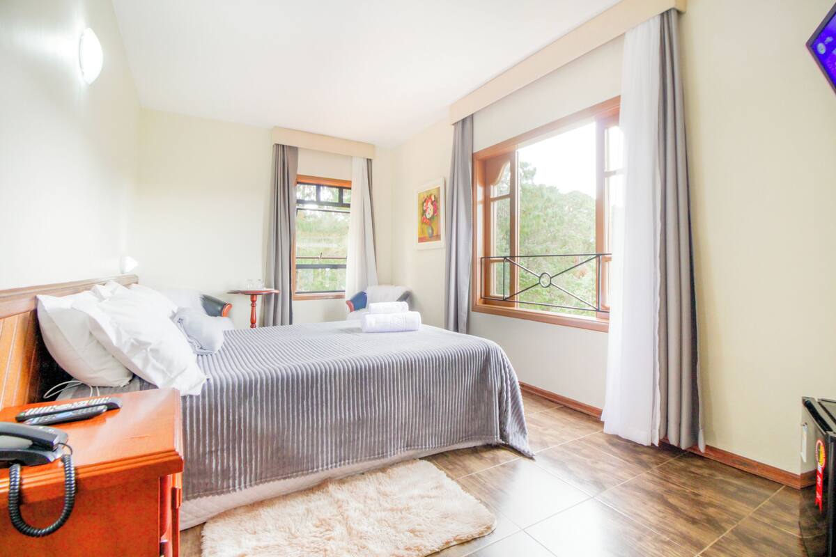 Une chambre à coucher avec un lit, une table de chevet et une fenêtre avec des rideaux.