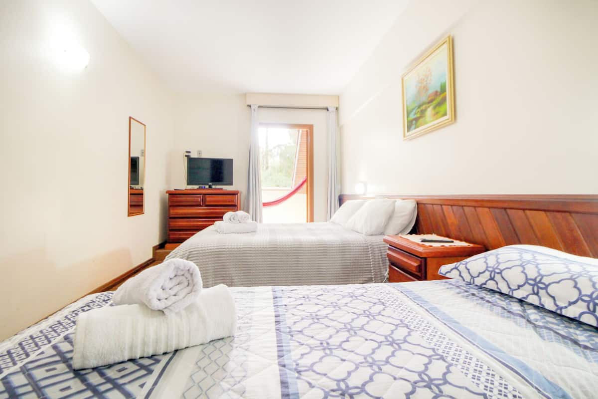 Une chambre d’hôtel avec deux lits, une télévision, une commode en bois et un tableau au mur.