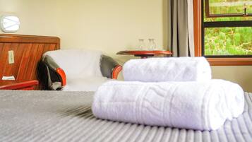 Relax in a serene room with a comfortable bed, a wooden headboard, and a view of lush greenery.