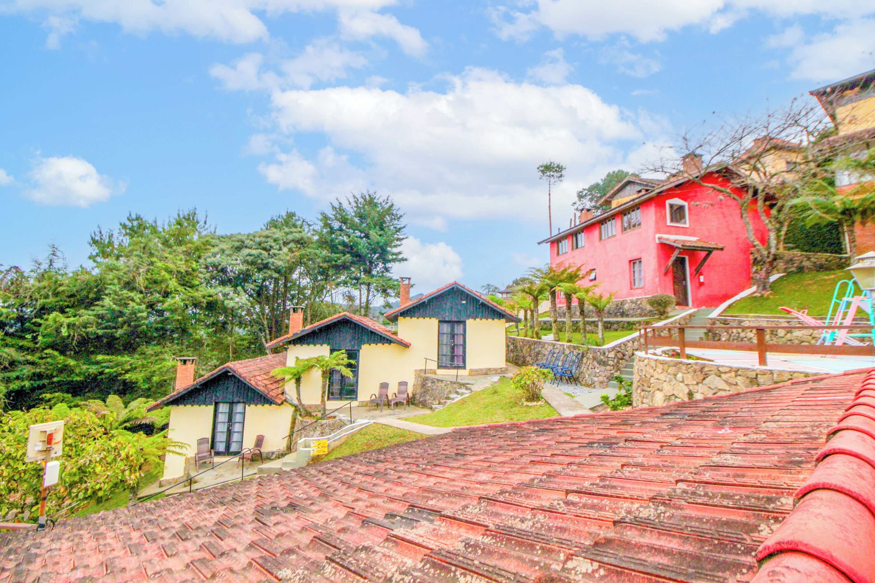 Un quartier résidentiel avec des maisons, un bâtiment à toit rouge et une végétation luxuriante.
