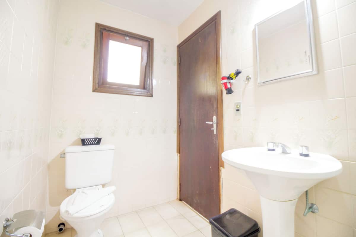 Une petite salle de bain avec des toilettes, un lavabo et une fenêtre située au-dessus des toilettes.