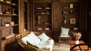 A traditional library room with bookshelves, a wicker chair, and a small table. - La Rambolitaine . (Poigny-la-Forêt)
