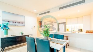 A modern dining area with a white table, teal chairs, and a black console. - Waterfront Retreat Ocean Views Pool Balcony (Darwin)