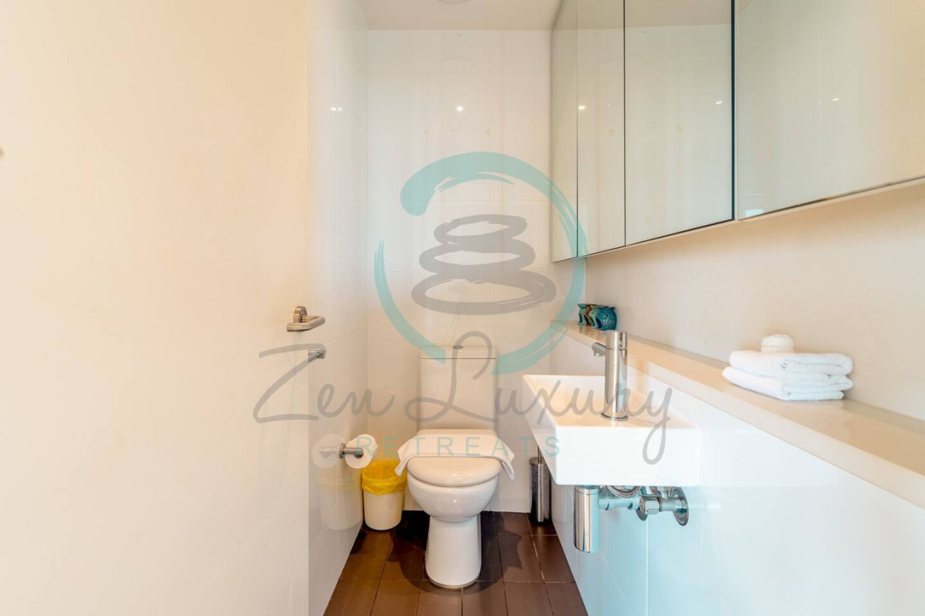 Et moderne badeværelse med toilet, vask og spejl.