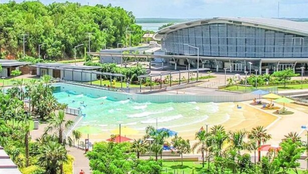 A modern hotel with a large swimming pool, a beach area, and a stadium-like structure. - Waterfront Retreat Ocean Views Pool Balcony (Darwin)