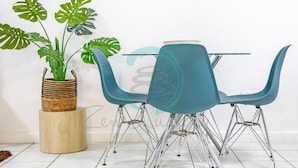 Een eetgedeelte met een tafel, vier stoelen, een potplant en een houten kruk.