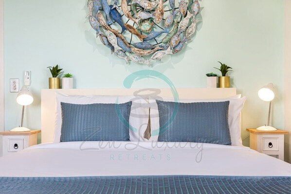 A neatly arranged bedroom with a large bed, two bedside tables with lamps, and a wall-mounted abstract art piece. - Zen Point Penthouse Private Top-floor 3BR Panoramic Ocean Harbour Views Darwin Waterfront (Darwin)