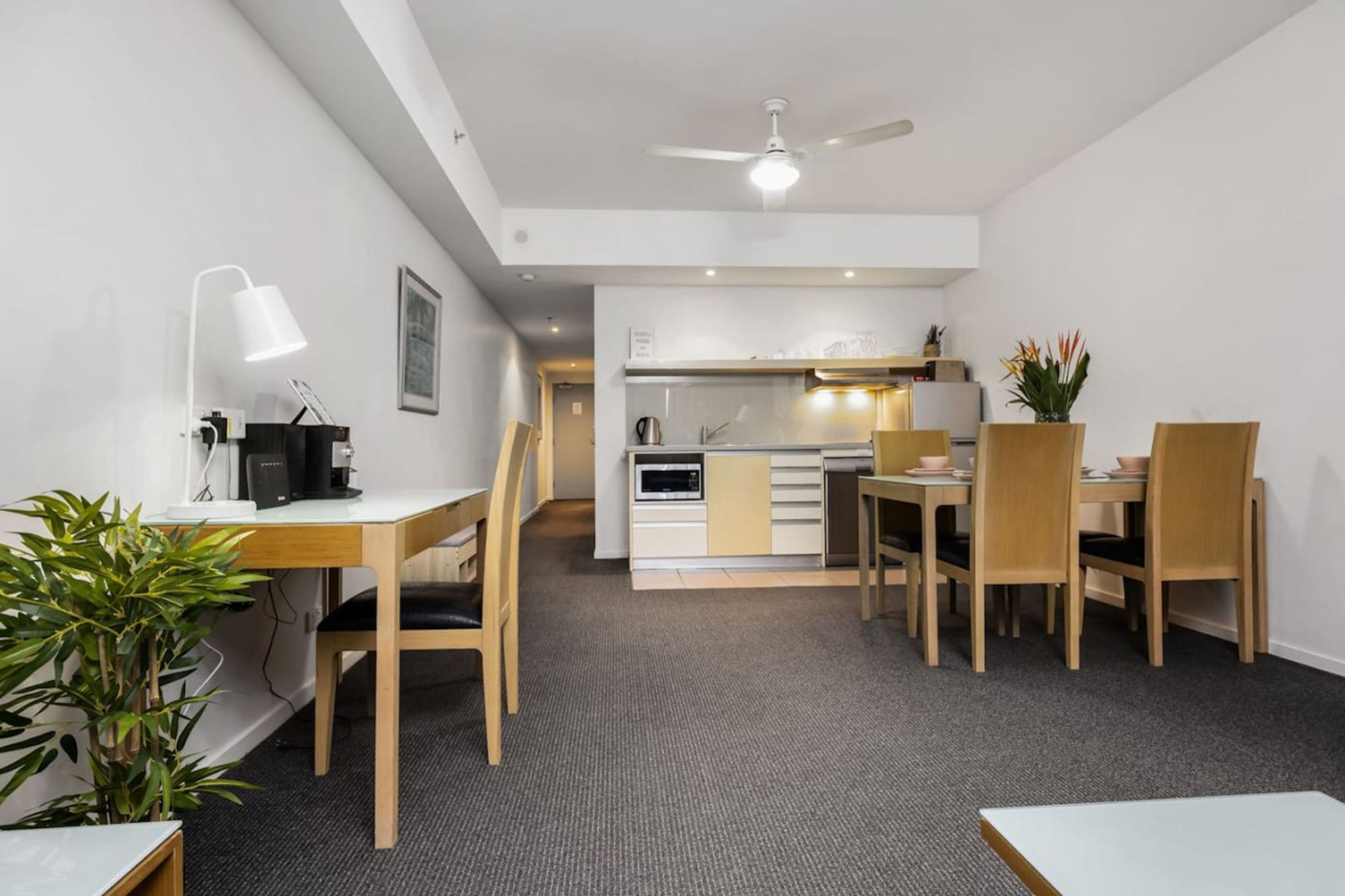 Una camera d'albergo moderna con zona pranzo, angolo cottura e ventilatore a soffitto.