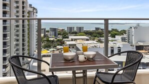 Een balkon met een tafel gedekt voor twee, met uitzicht op een stadsbeeld en de zee.