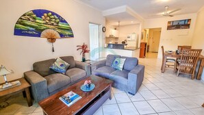 A living room with two sofas, a coffee table, and a dining area with a table and chairs. - Zencity Balcony Outdoor Dining Mindal Markets (Larrakeyah)