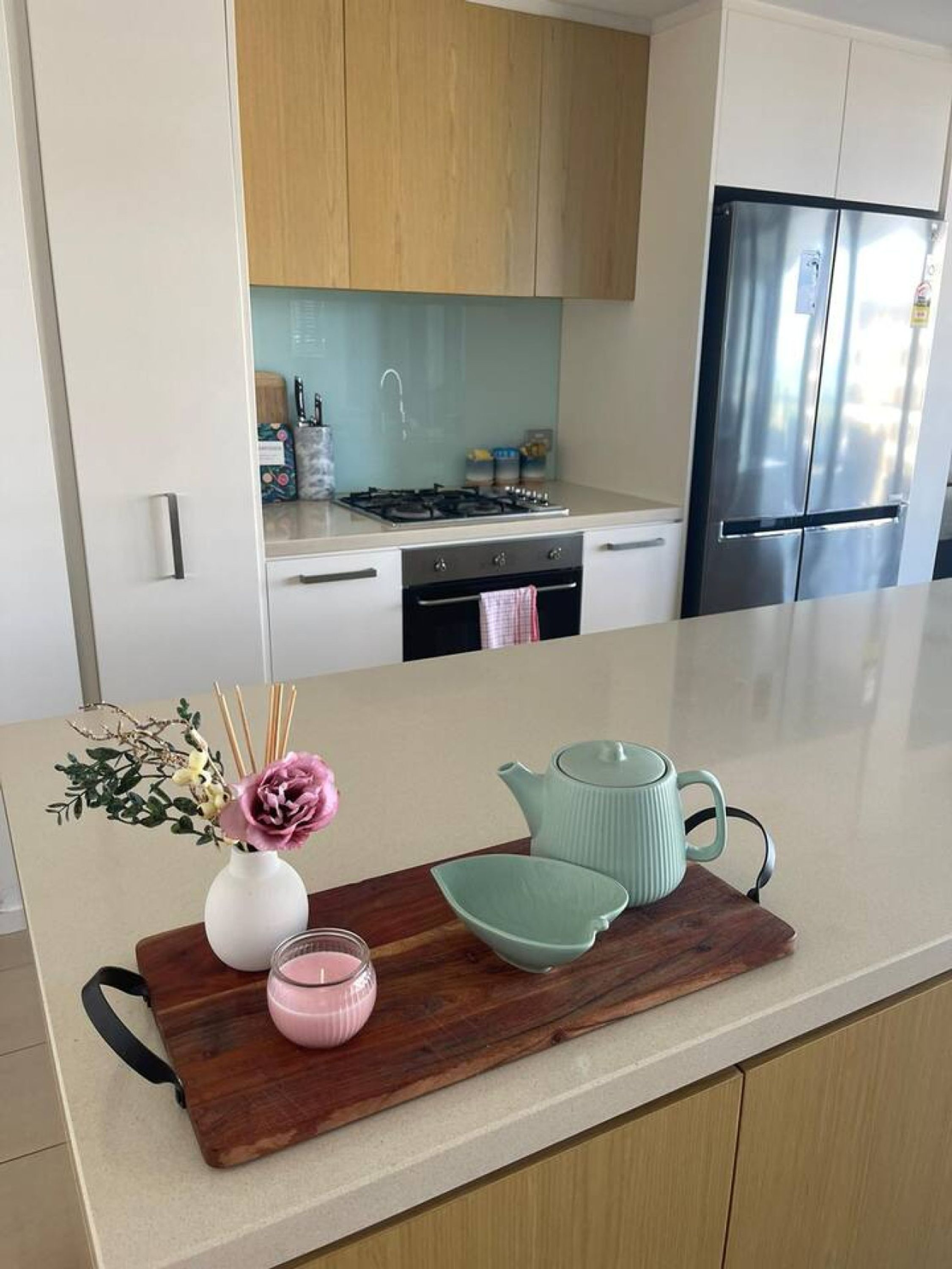 A modern kitchen with a stainless steel refrigerator, a gas stove, and wooden cabinets.