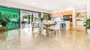 A modern kitchen with a central island, built-in appliances, and a large window overlooking greenery. - Fred s at Fannie Bay - NT (Fannie Bay)