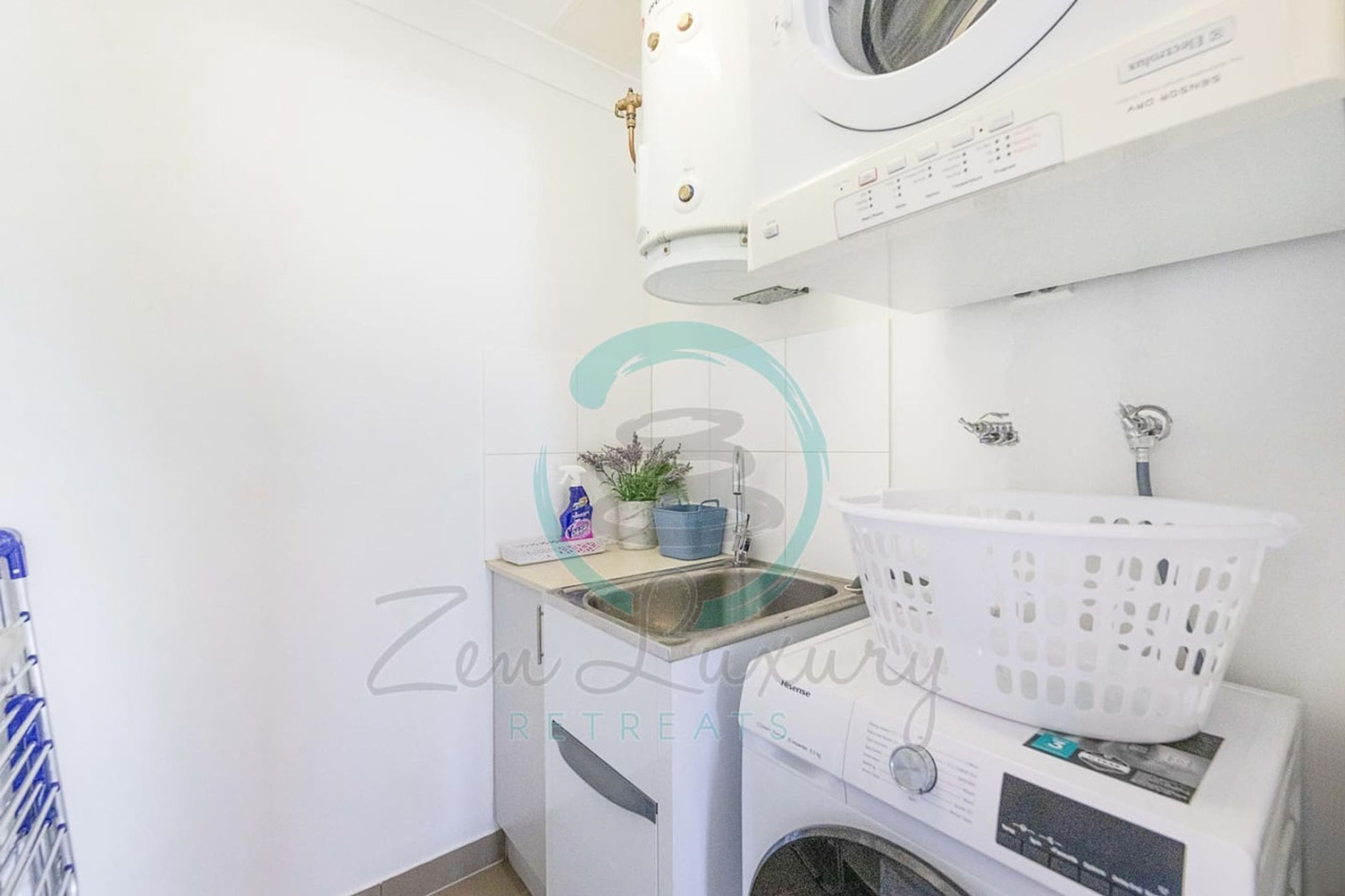Une buanderie équipée d’un lave-linge, d’un sèche-linge et d’un évier.
