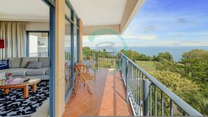 Een balkon met uitzicht op zee, een bank, een tafel en een stoel.