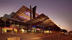 A modern building with a unique roof structure and large glass windows. - Coastal Splendor Seaview Pool Balcony Dining (Darwin)