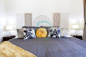 A neatly arranged bedroom with a large bed, decorative wall panels, and two bedside lamps. - Reef-side Splendor City Vistas Pool Workspace (Darwin)