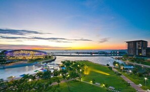 A waterfront hotel with a modern glass building, a marina, and a bridge in the background. - Reef-side Splendor City Vistas Pool Workspace (Darwin)
