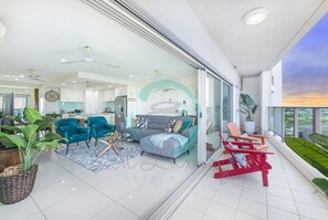 A modern living room with a sofa, chairs, and a balcony with plants. - Zen Seabreeze Workdesk Balcony Dining Seaview (Darwin)