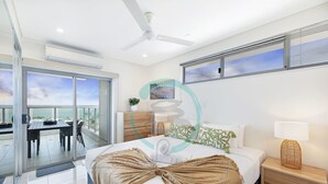 A modern bedroom with a bed, bedside table, and a view of the sea through large windows. - Zen Seabreeze Workdesk Balcony Dining Seaview (Darwin)