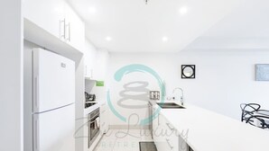 A modern kitchen with white cabinetry, a built-in oven, and a stainless steel sink. - Zen Ocean Meadows Sea View - Pool - Outdoor Dining (Darwin)