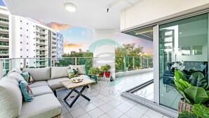 Um apartamento moderno com varanda, sofá, mesa de jantar e plantas em vasos.